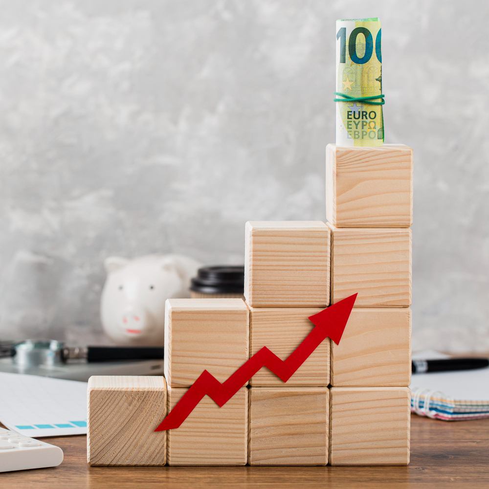 Wooden blocks stacked in growing order with a roll of bank notes on top